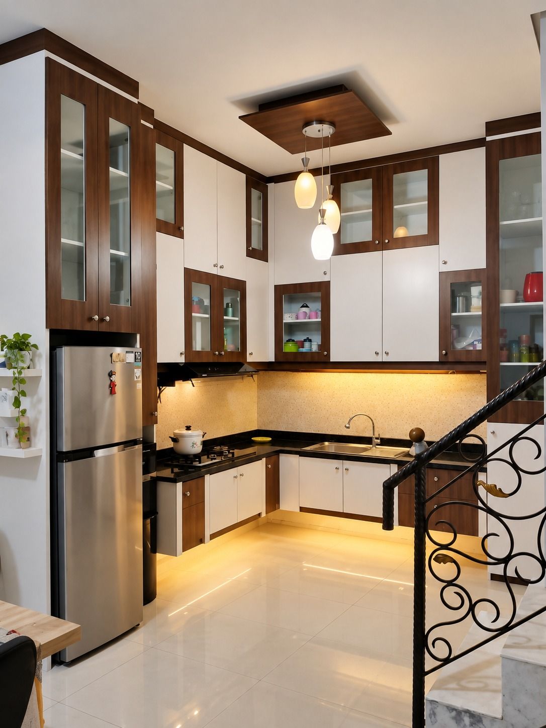 Dapur dilihat dari arah tangga, memperlihatkan lemari tinggi berpintu kaca dan cahaya hangat di bawah kabinet.