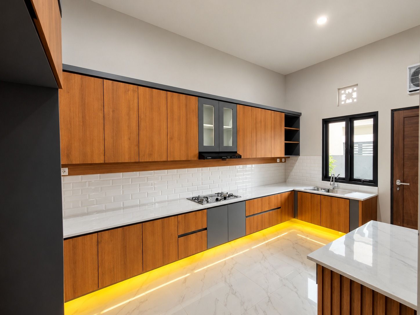 Deret kabinet dapur bermotif kayu sepanjang dinding dengan lampu di bawahnya.