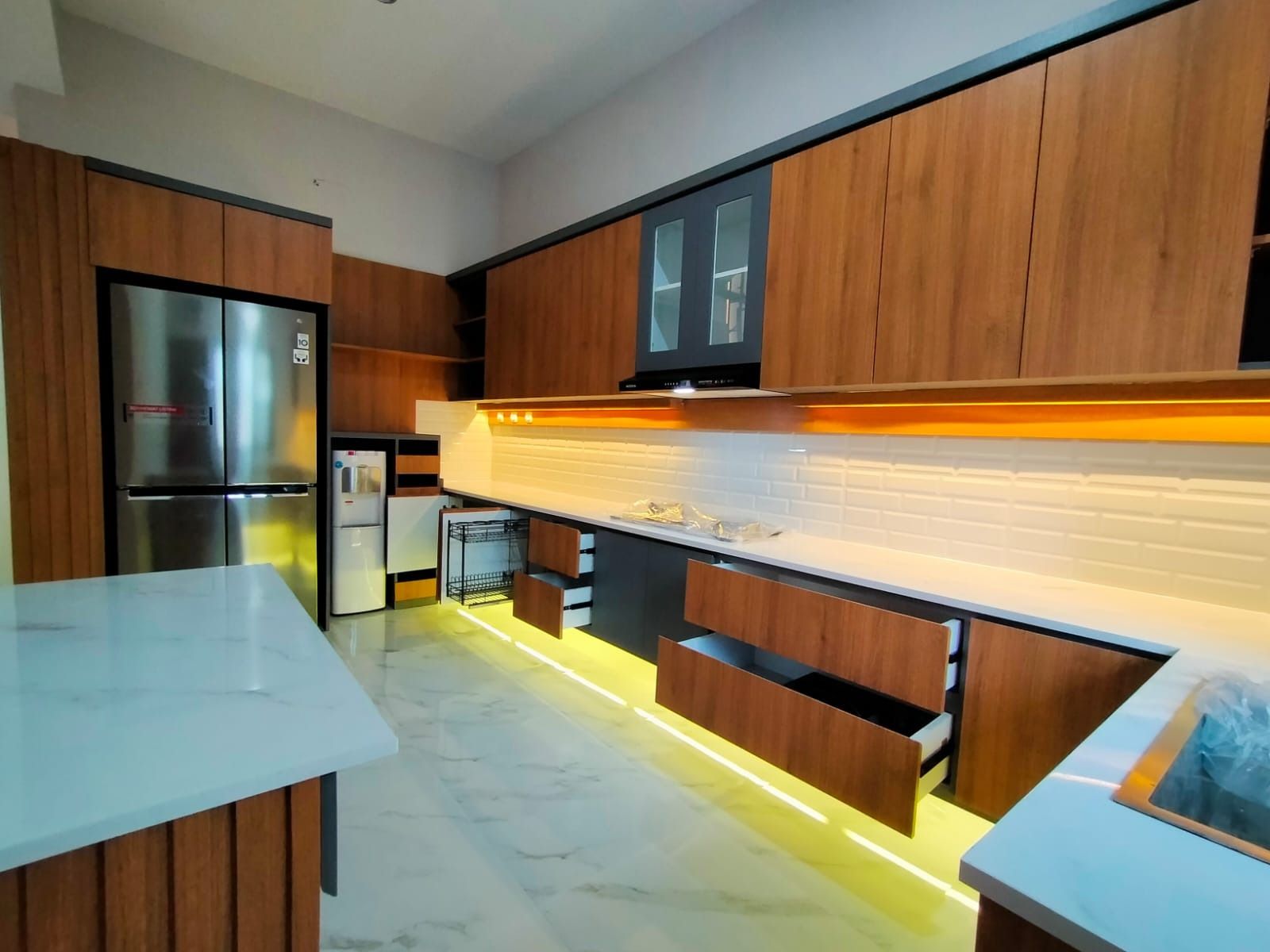 Sudut lain dapur memperlihatkan meja kerja dan kabinet di dekat jendela.