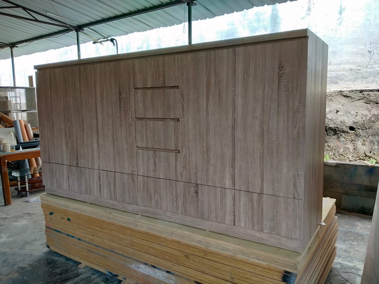 Lemari penyimpanan lebar dengan pintu tertutup dan pegangan tanam, berdiri di area workshop.