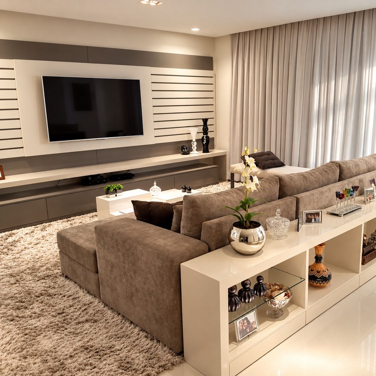 Backdrop TV berbilah putih dengan pita abu-abu tua, meja TV panjang, dan konsol putih berak kaca di belakang sofa.