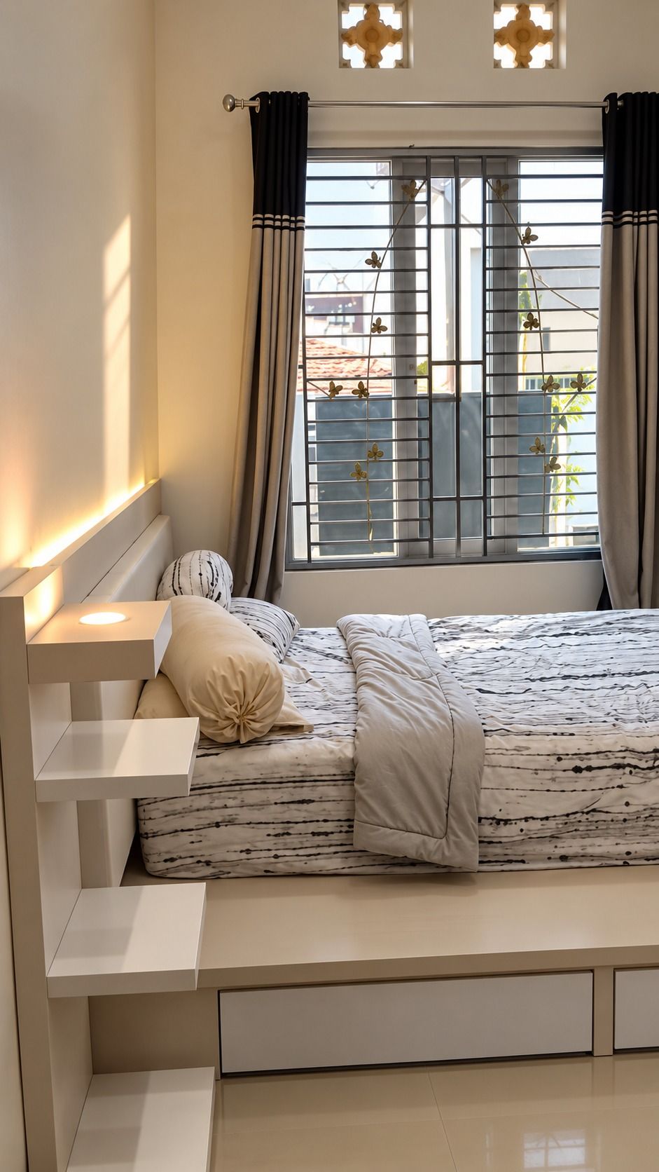 Kamar bernuansa putih dengan ranjang berlaci, headboard berlampu, dan rak samping bertingkat di dekat jendela.